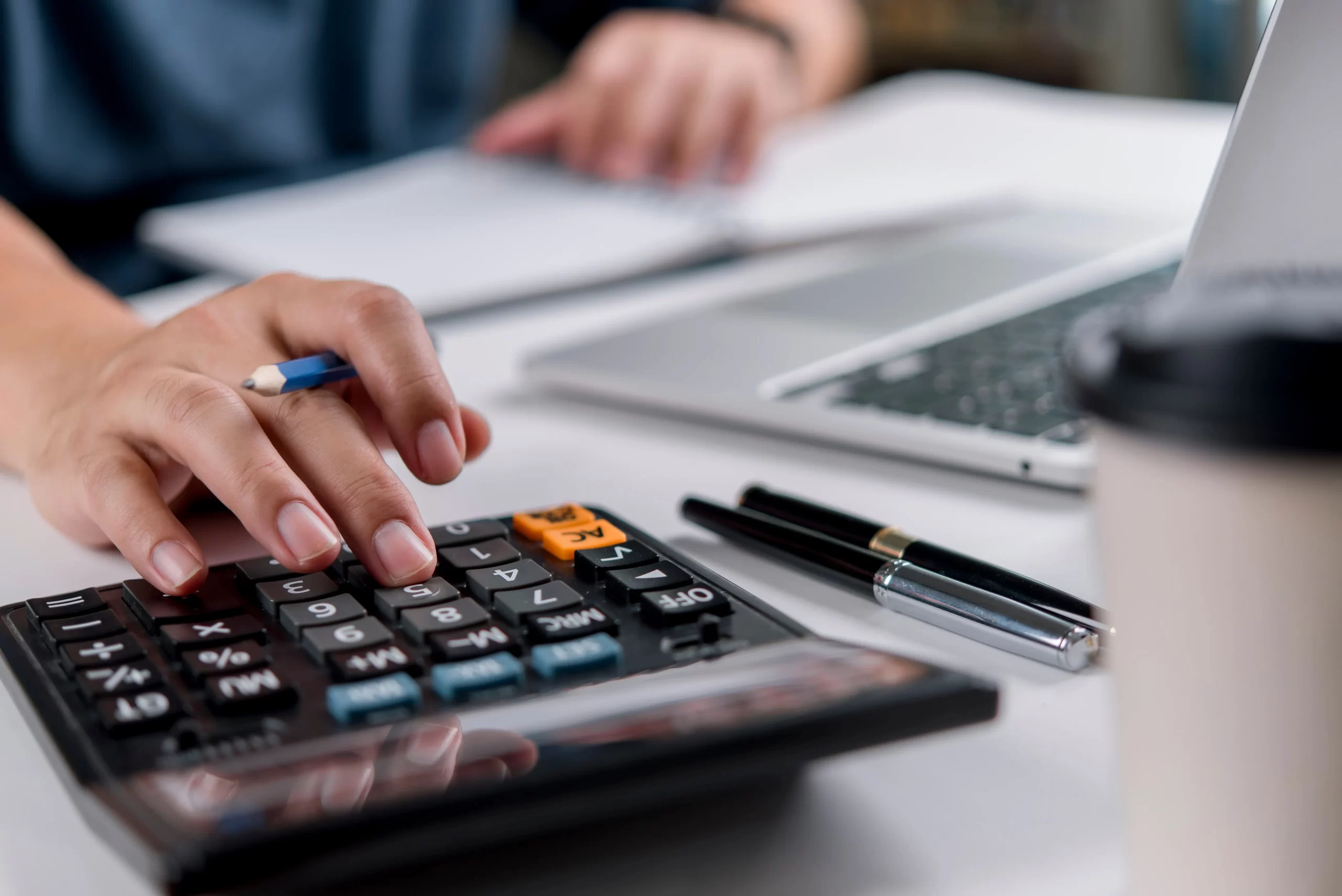 person sitting at desk using calculator with papers in front of them