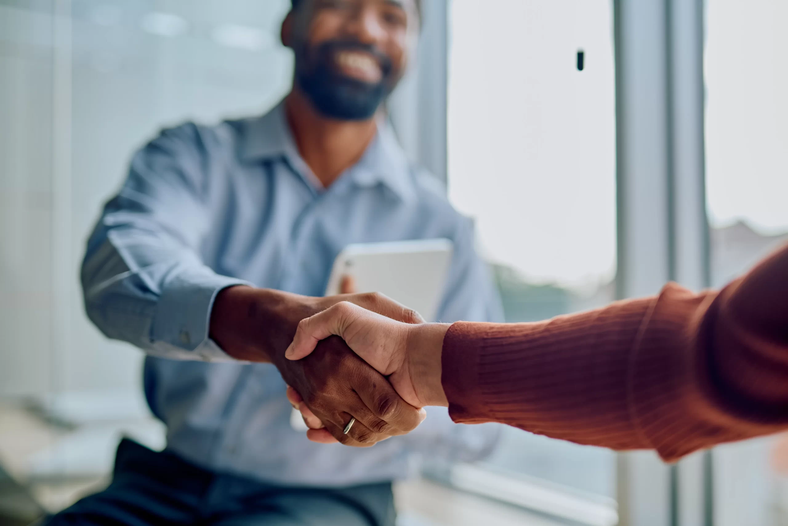 Two business professionals shaking hands, symbolizing successful partnership, agreement, deal, and collaboration in an office setting