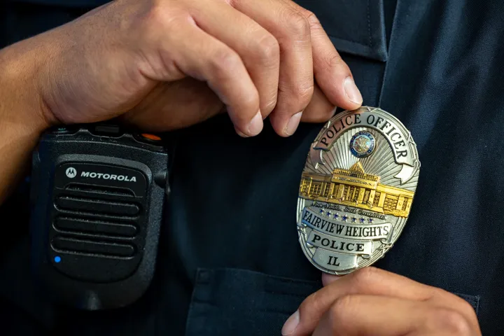 fairview heights police officer adjusting police badge on uniform.