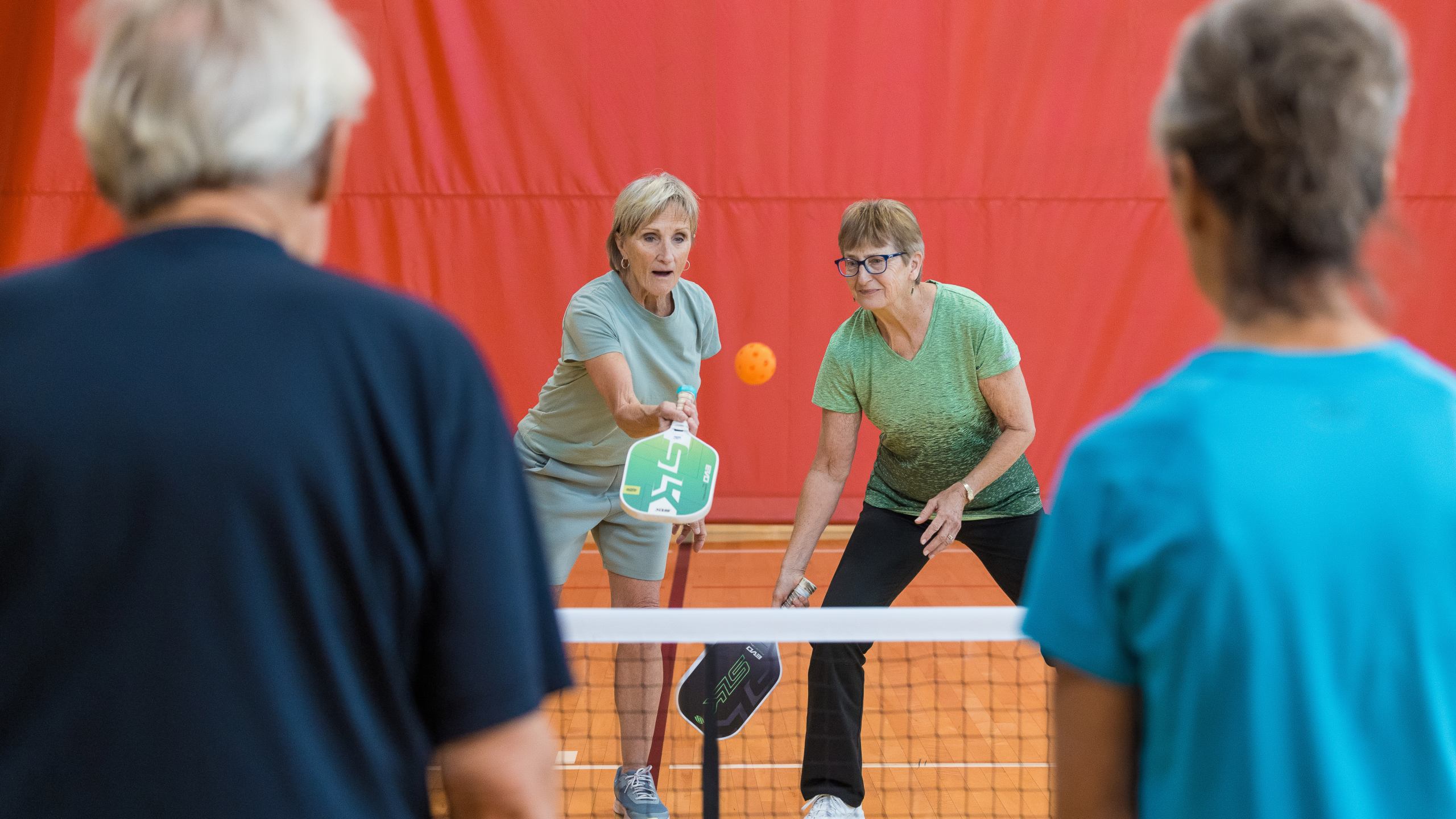 Group of people playing pickleball at the rec in fairview heights, two men against two women.